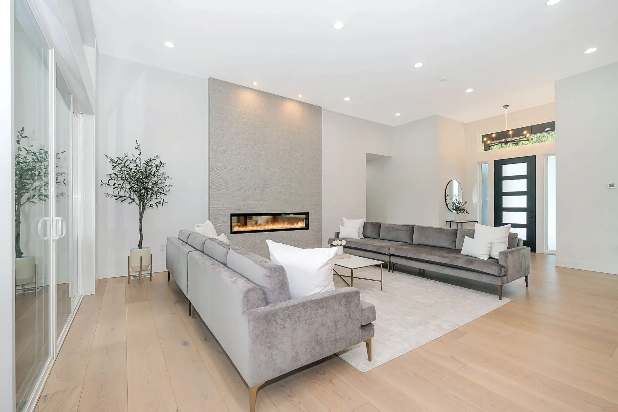 Modern gas fireplace insert in open-concept living area with light wood flooring and contemporary furnishings.