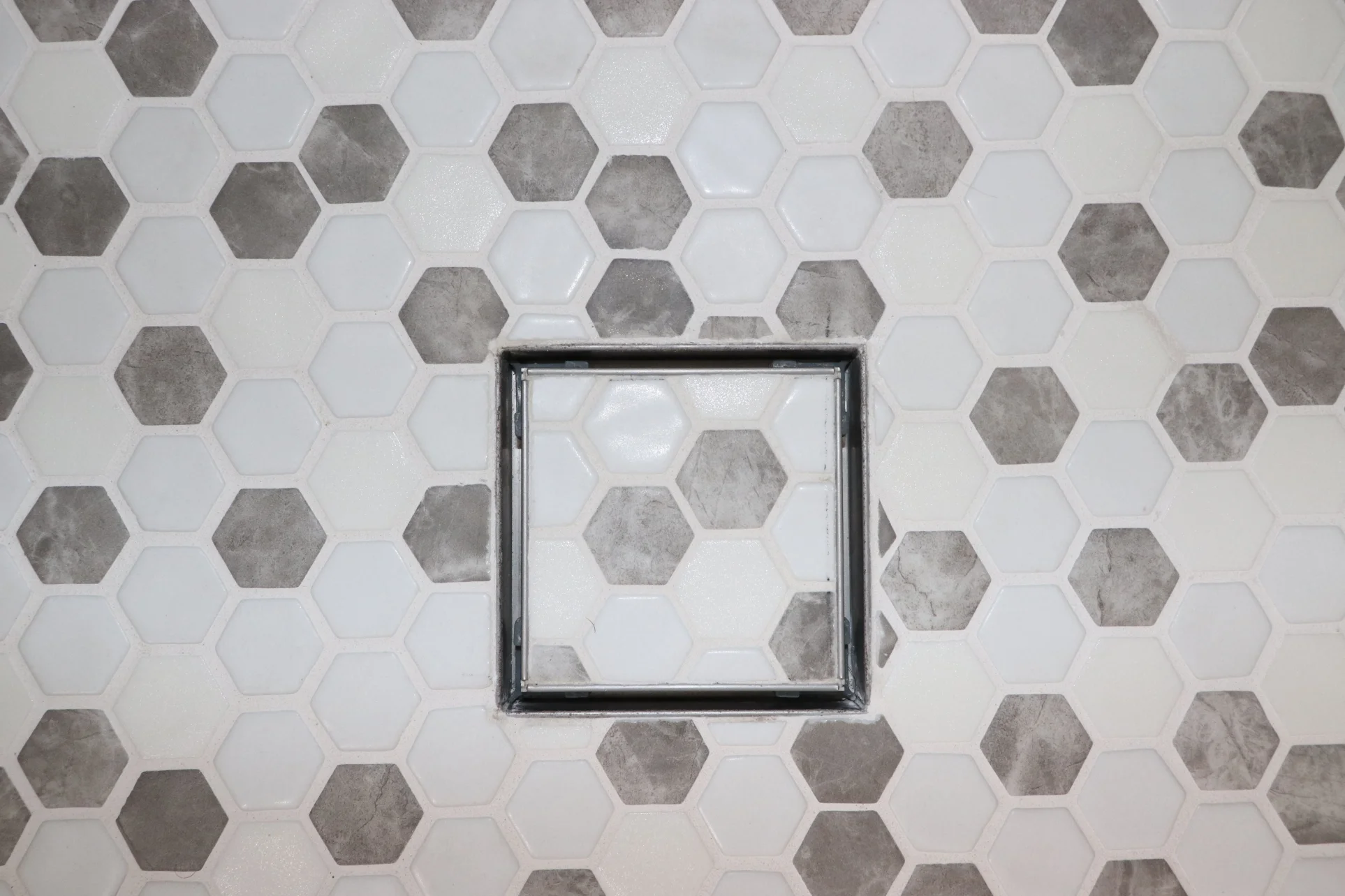 Close-up of kitchen backsplash tile with chrome outlet cover, showing electrical considerations in remodel design.